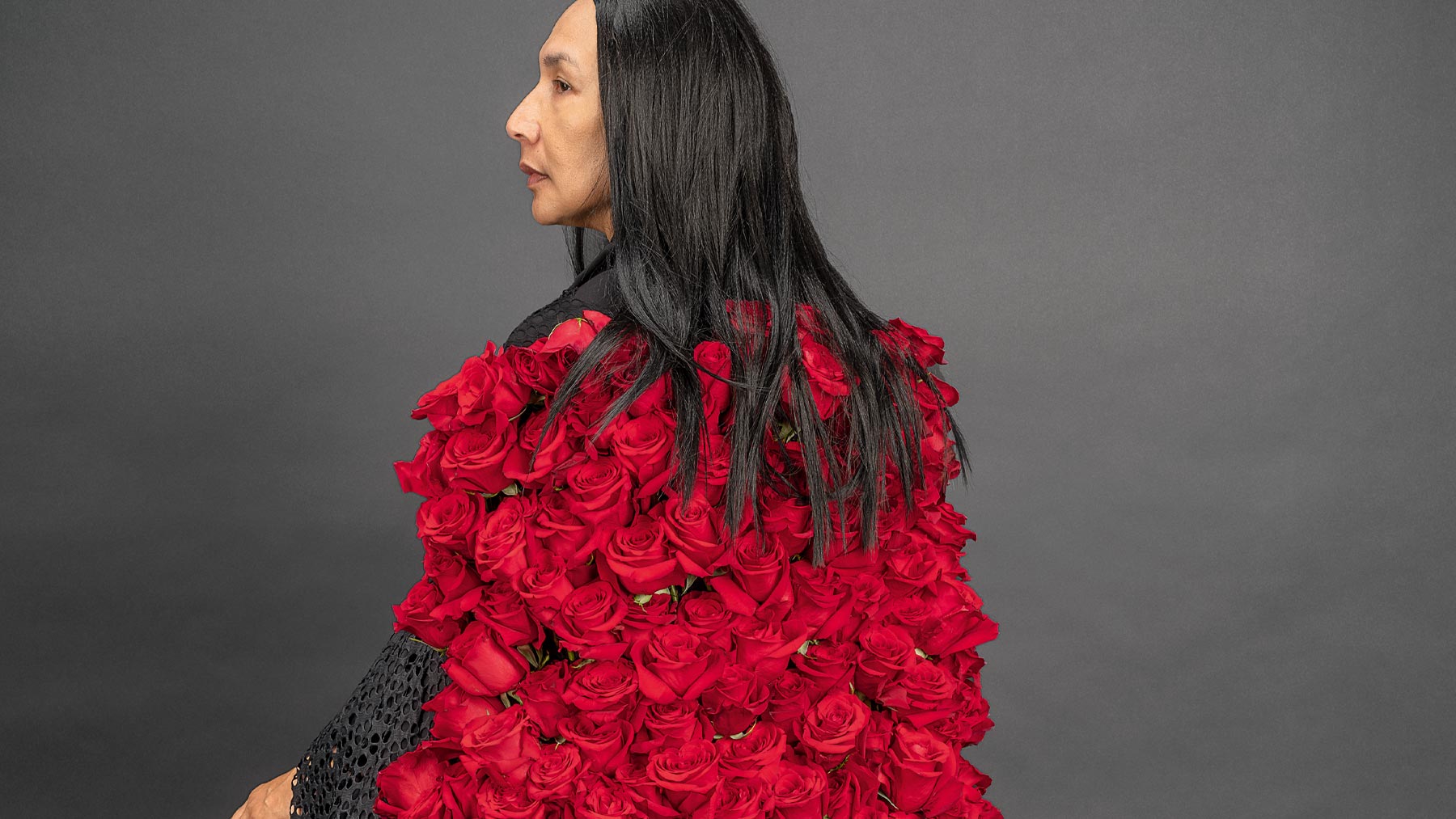 Native American woman with long hair wearing a dress made of red flowers