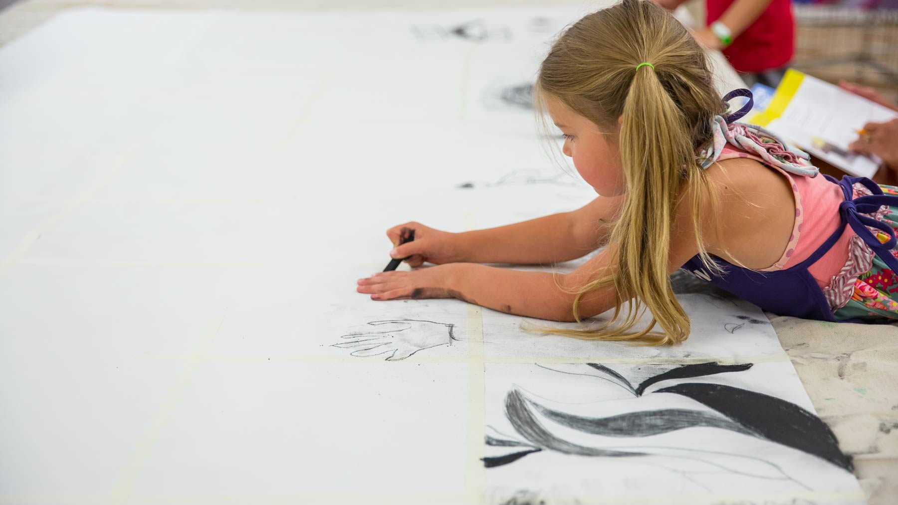Young girl drawing on a very large piece of paper