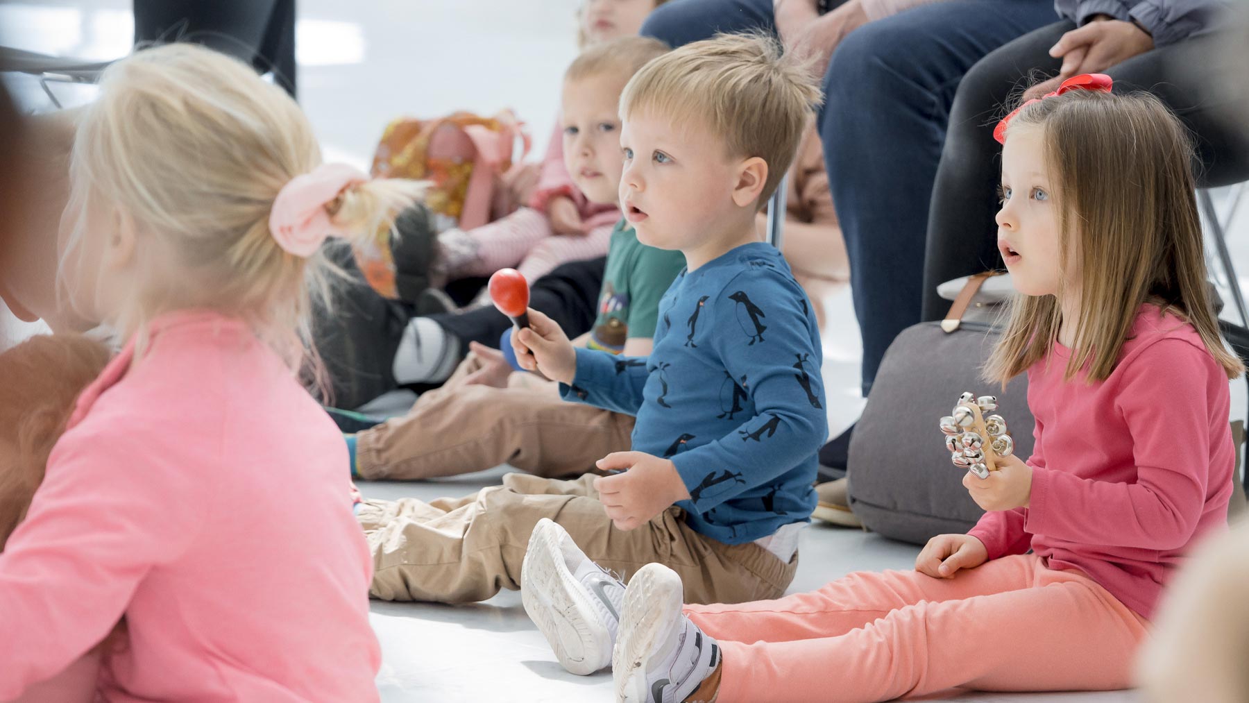 Three children listening while holding small instruments