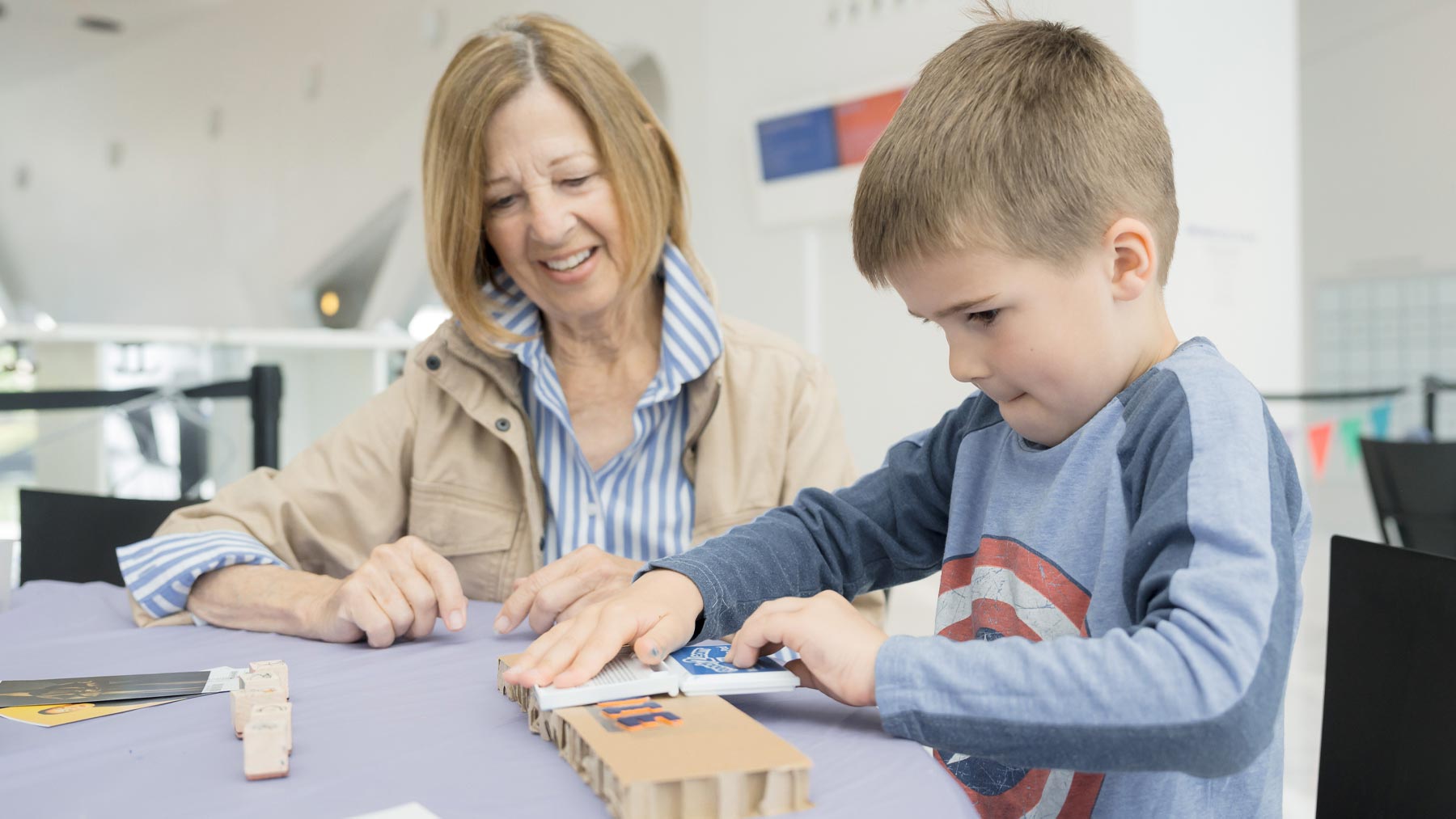 Woman watches as a young boy creates something with stamps