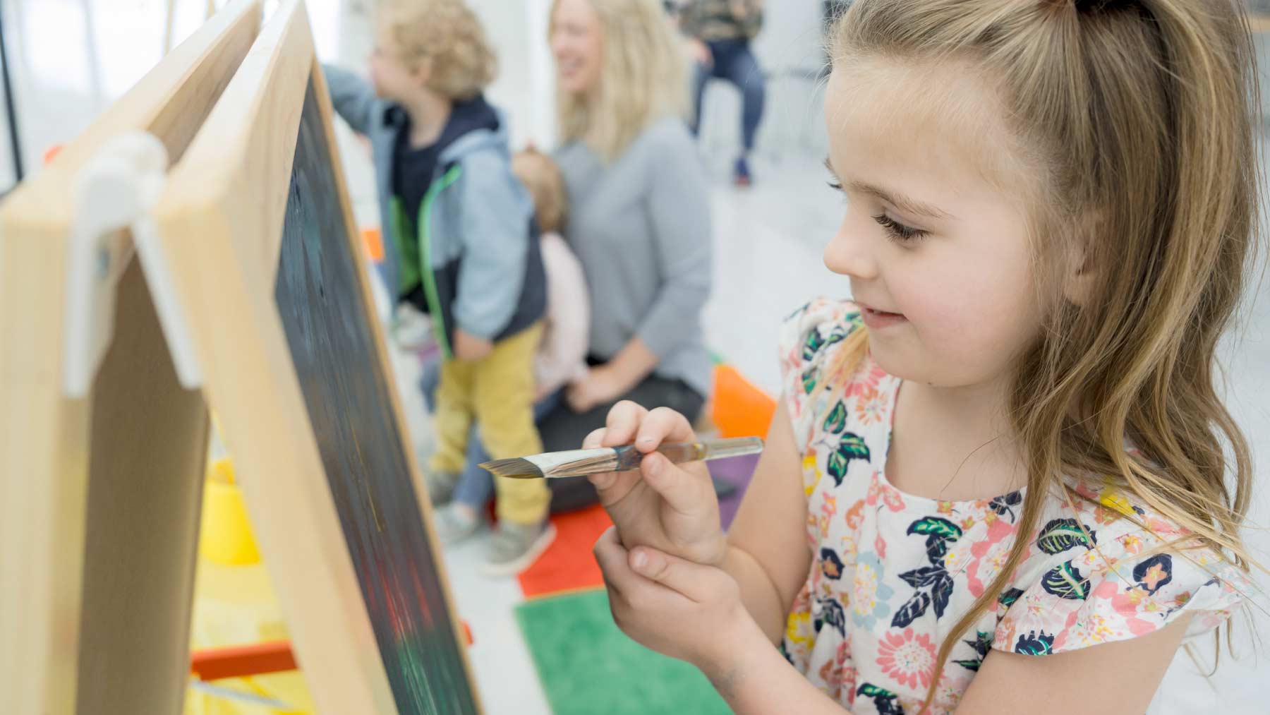 Little girl painting on an easel