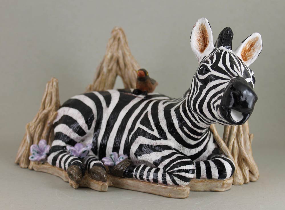Ceramic teapot in the shape of a baby zebra sitting on tree branches with a bird on its back