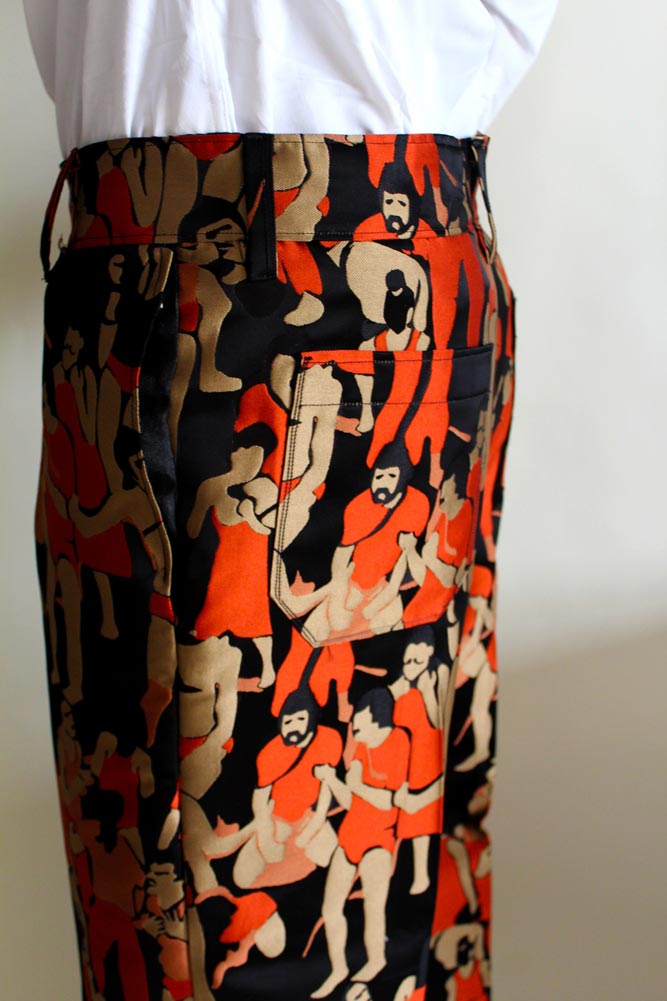 Close up of a pair of orange and black slacks with a pattern of people