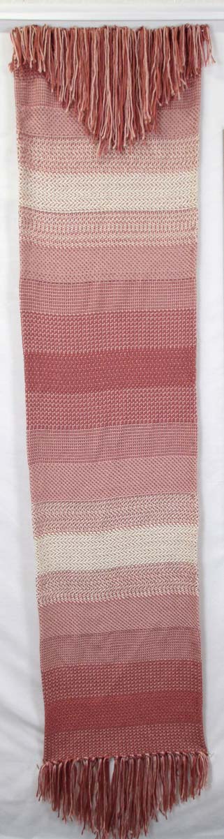 Long woven wall hanging in a pink-toned gradient with frayed ends
