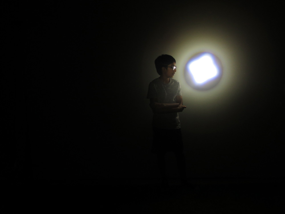 Young boy in a pitch dark room with a spotlight shining on him