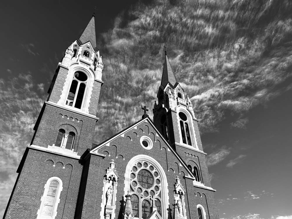 View looking up at a brick church with steeples on each side