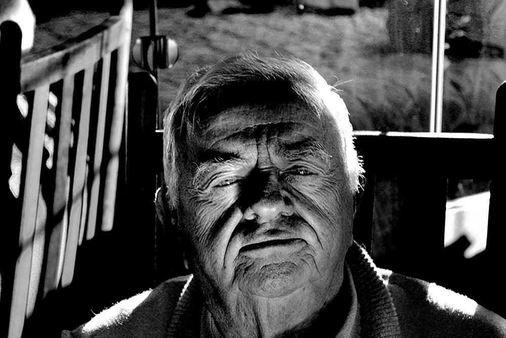 Close-up of an elderly man sitting on a porch swing