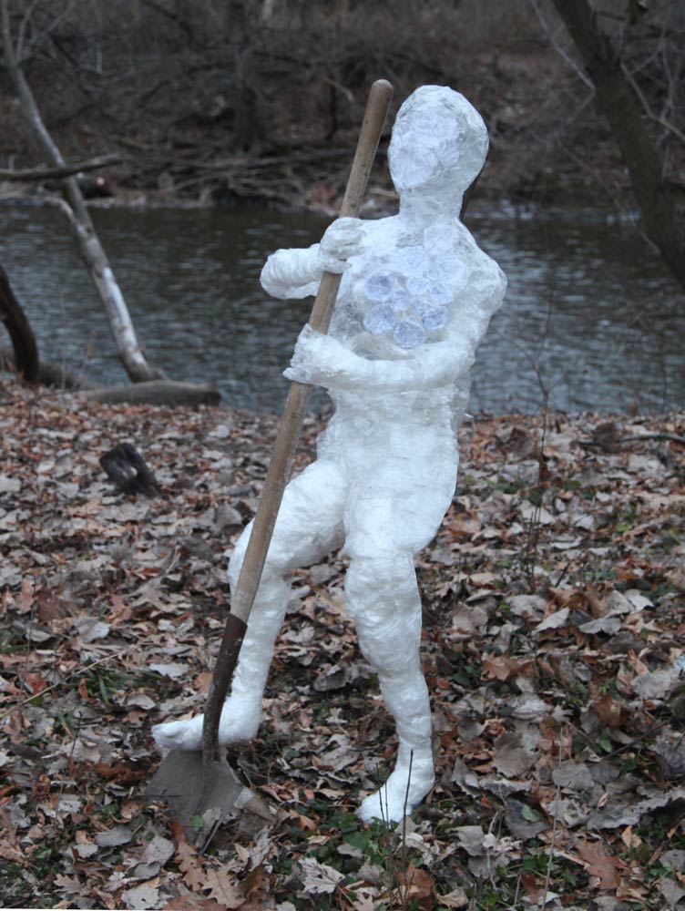 Sculpture of a person made out of plastic wrap holding a shovel and digging into the ground