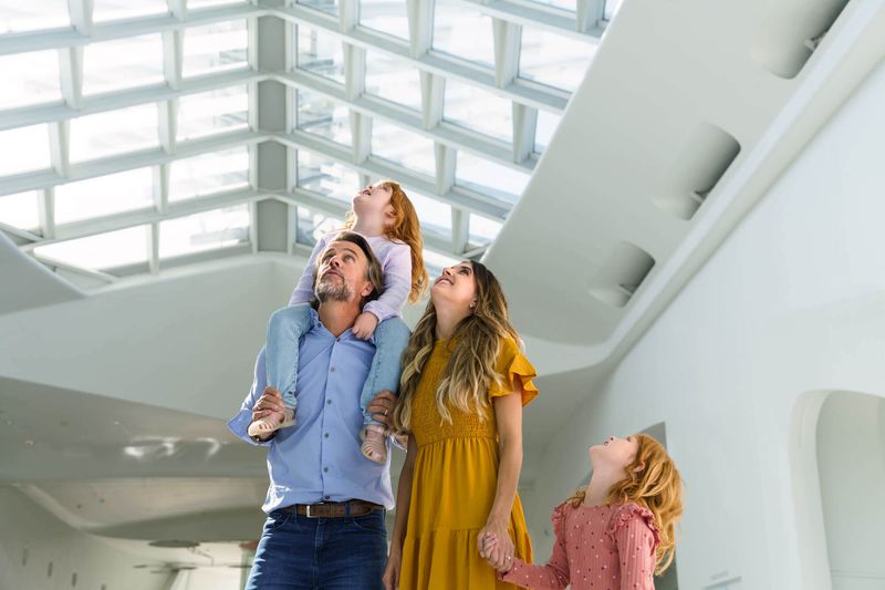 A family of four stands at the edge of Windover Hall and look up at the architecture in admiration.