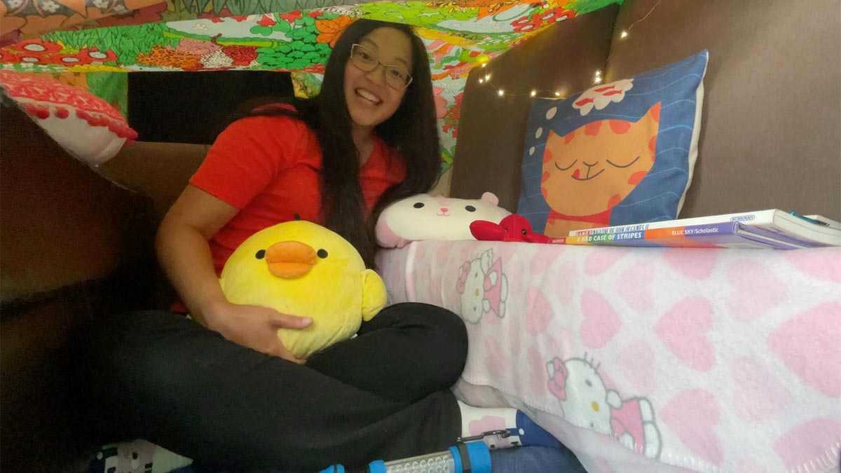 Young woman sitting under a blanket fort with pillows
