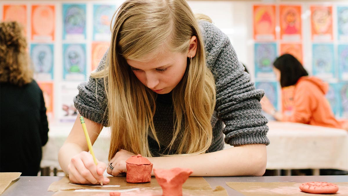 Young girl working on a clay sculpture