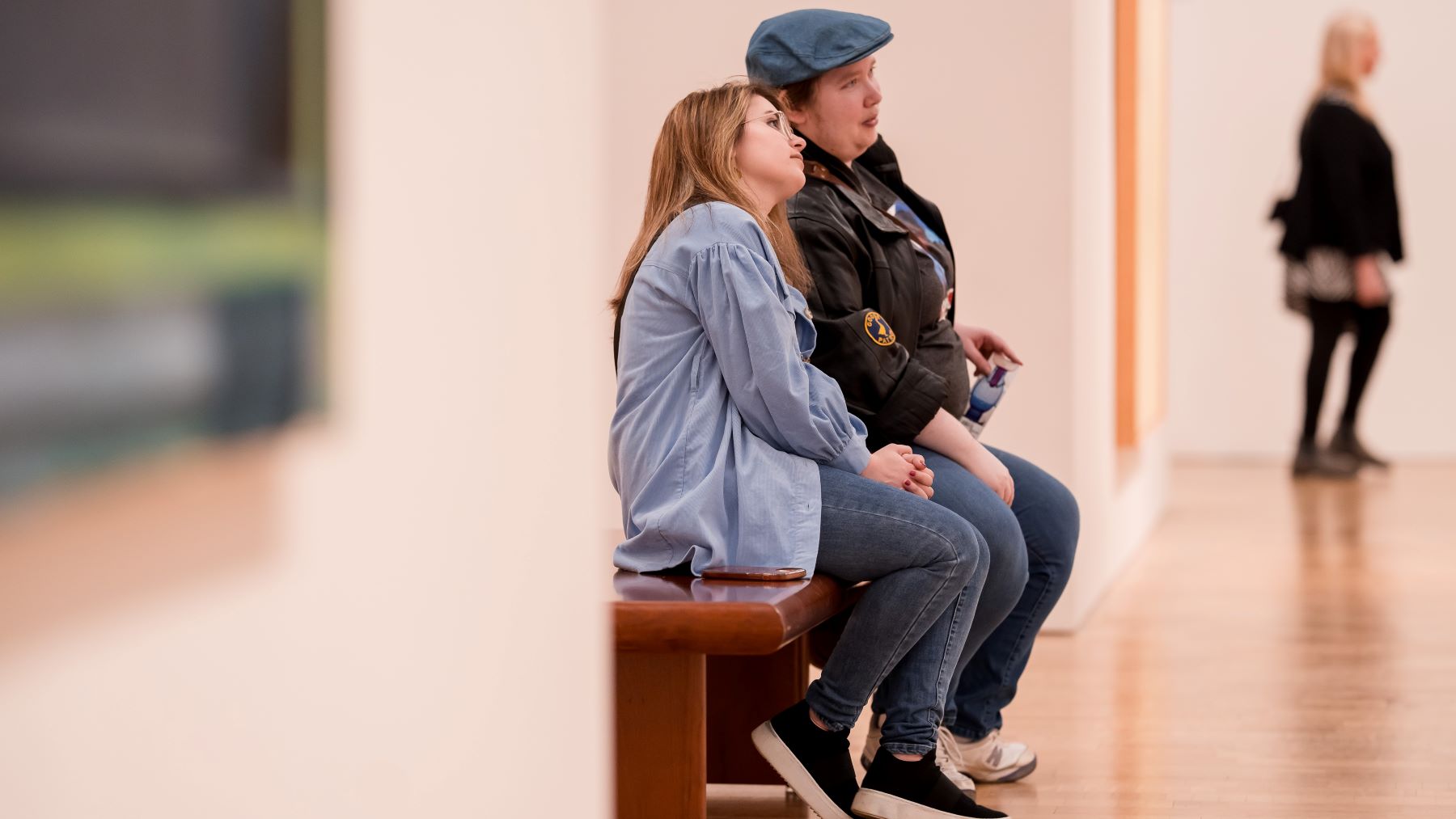Two people sitting on a bench at the Milwaukee Art Museum looking at art