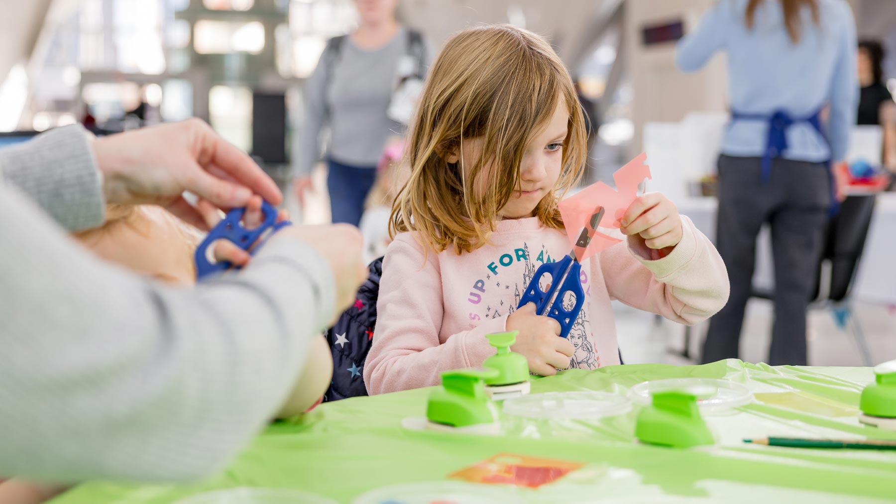 Little girl cutting paper with scissors
