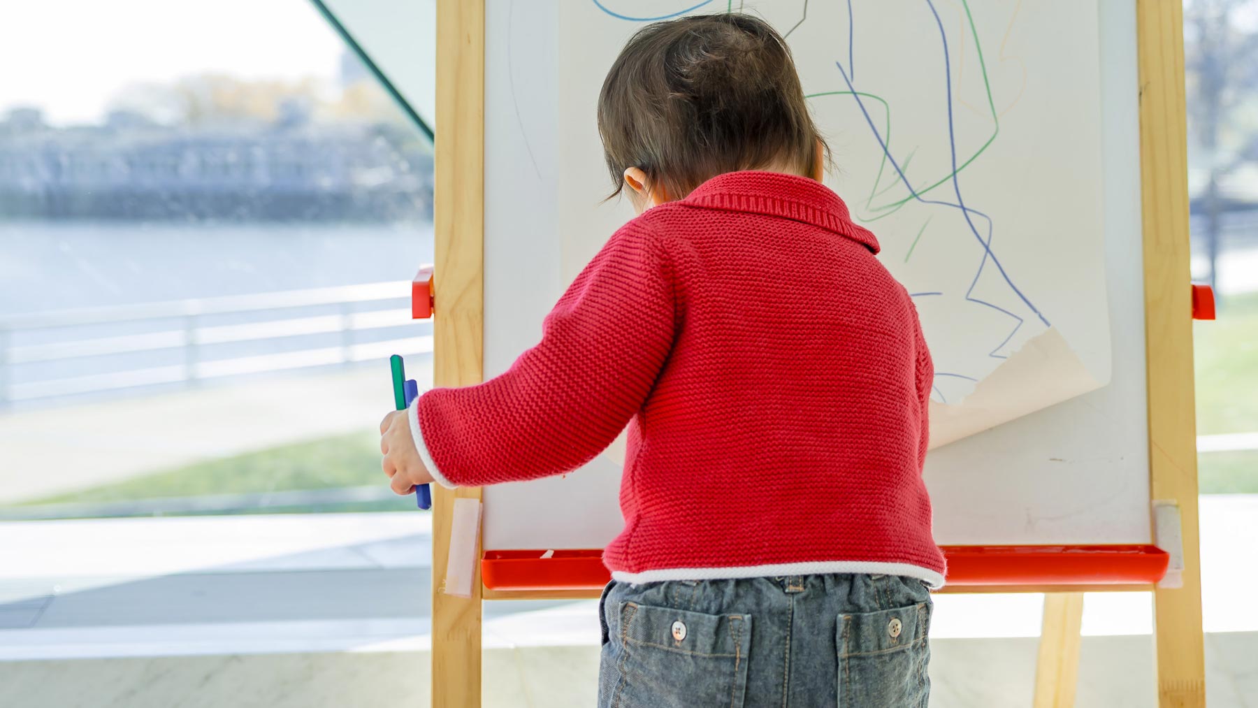 Young child drawing on an easel