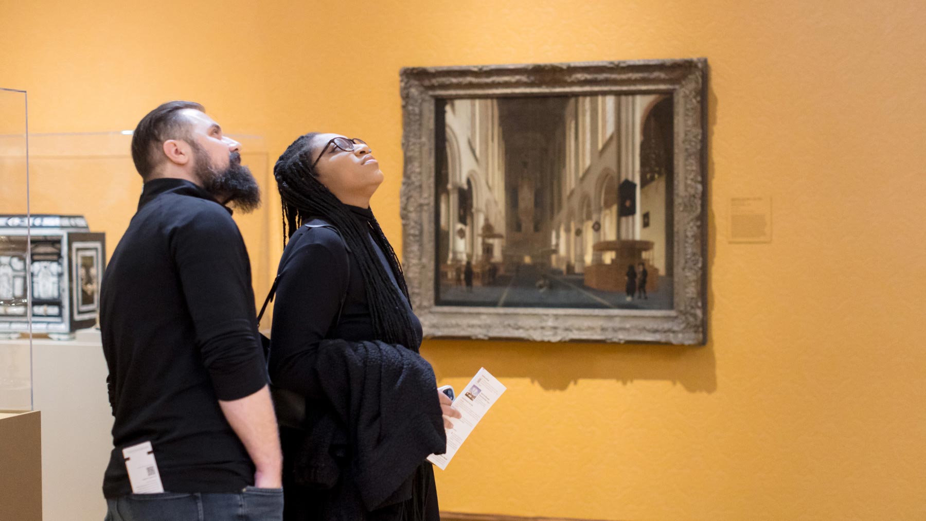 Two people admiring a work of art on the wall