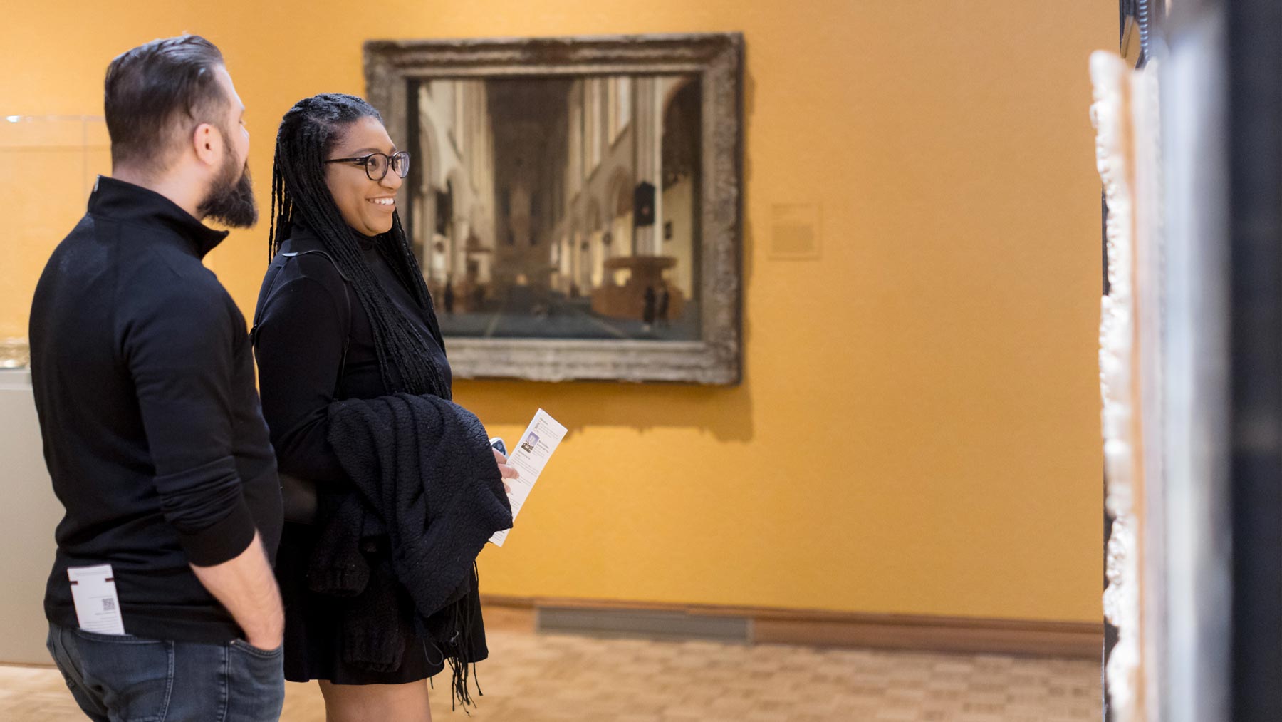 Two people admiring a work of art on the wall