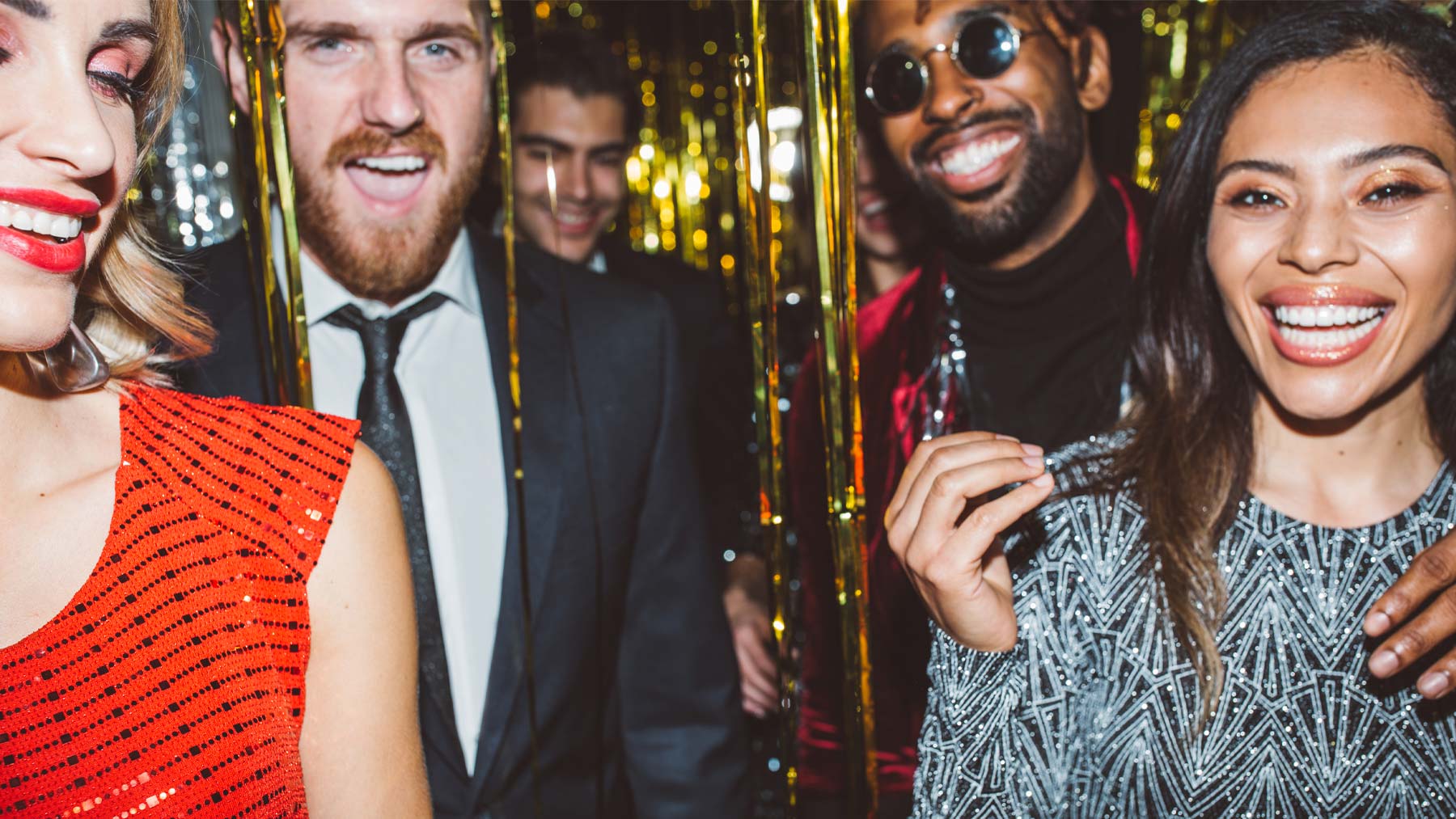 Five young adults posing in front of gold streamers