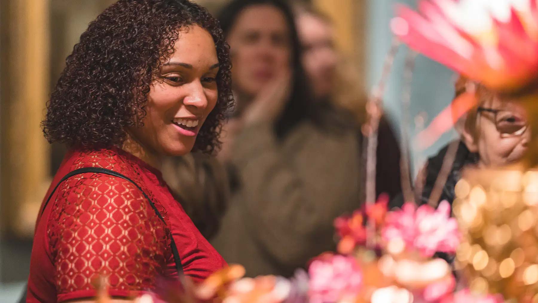 Woman smiling while admiring a floral arrangement based on a work of art