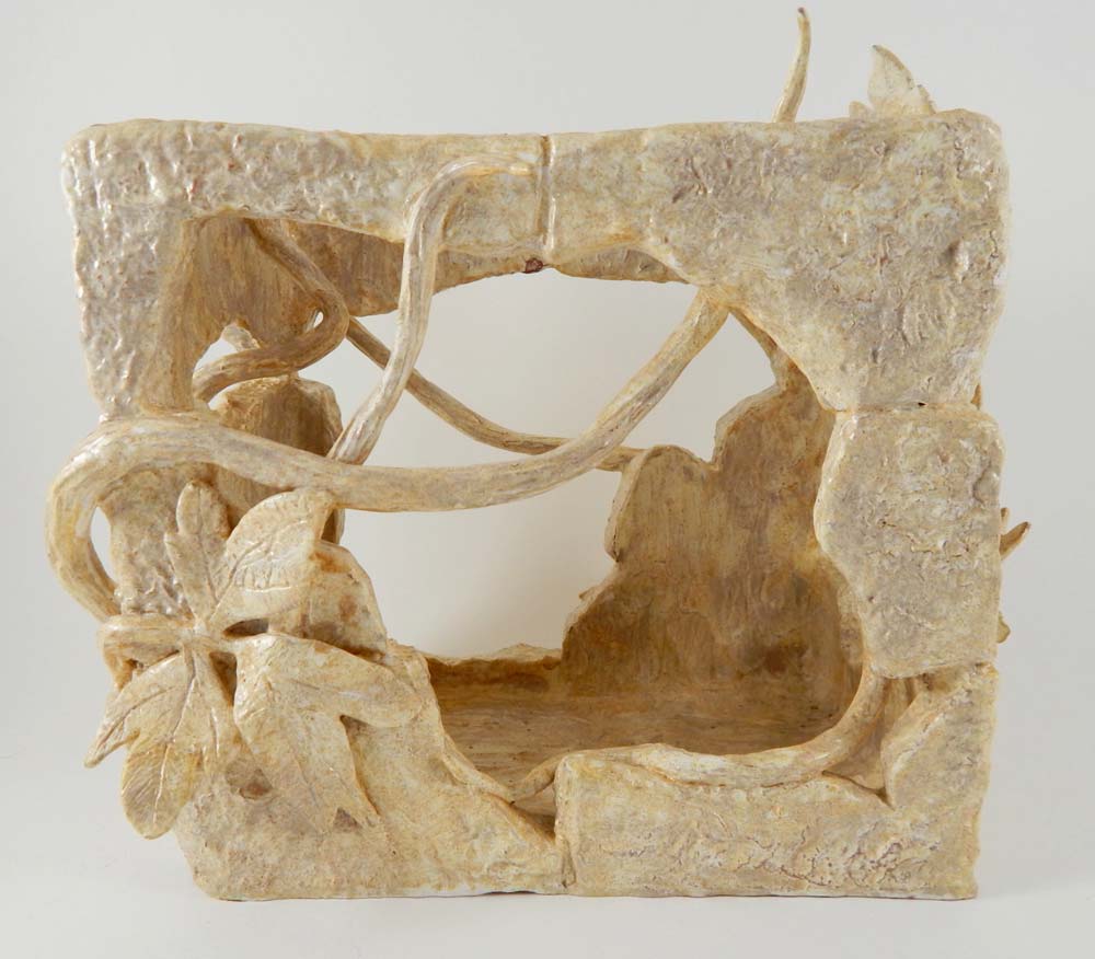 Ceramic sculpture of a square brick with vines growing through the middle