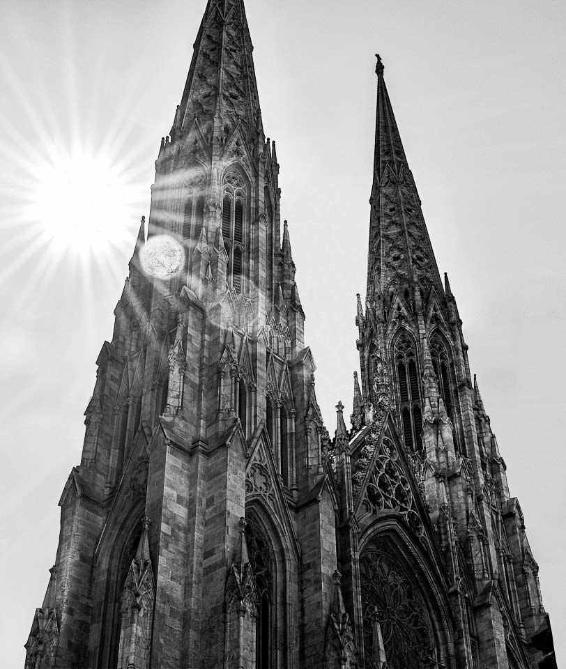 Black and white image of a victorian-styled church with a bright sunshaft